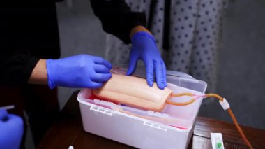 Enjeksiyonla pratik dersi. Pratisyen bir kuklanın damarına iğne yapıyor. Manikin koluna iğne batırma işlemi. Yakın plan..