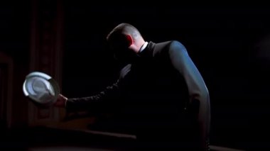 Aktör tiyatro sahnesinde bir gösteri yapıyor. Siyah takım elbiseli adam şapkasını giydi ve karanlıkta spot ışıklarının karşısında dans etmeye başladı..