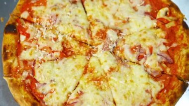 Hazır pizza peynirle serpiştirilmiştir. Eritilmiş peynir ve diğer malzemelerle iyi pişmiş pizza. Lezzetli çerez. Yakın plan. Üst görünüm.