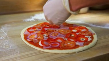 Pizza hazırlığı. Eller pizza hamurunun üzerine soğan dilimleri koyuyor. Pizza yapma süreci. Şef lezzetli pizza için yemek hazırlıyor..