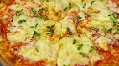 Lezzetli pizza. Eritilmiş peynir ve pizza üzerine yeşil lahana. Masada dönen iştah açıcı pizza. Yakın plan..