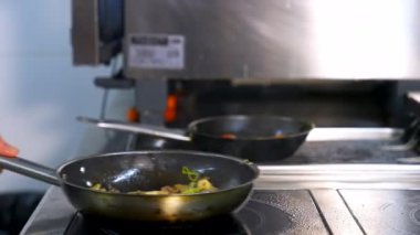 Profesyonel şef mantar pişiriyor. Aşçı kızartma tavasında mantar hazırlıyor ve üzerlerine sos döküyor. Lokantada nefis yemekler.