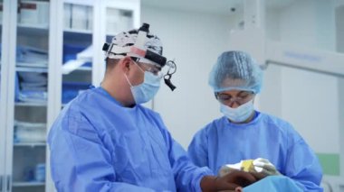 Ameliyathanede ameliyat. Doktor ve mavi üniformalı bir hemşire modern klinikteki bir hastaya ameliyat yapıyorlar..