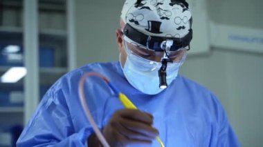 Tıbbi kıyafetli doktor ameliyat yapıyor. Klinikte ameliyat sırasında tıbbi aletlerle çalışan profesyonel bir uzman. Sağlık hizmetleri kavramı.