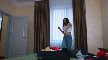 Neşeli kadın valizini topluyor. Dans eden mutlu bir kız ve seyahatten önce bavula bir şeyler koyuyor. Rahat bir otelde güzel bir kadın..