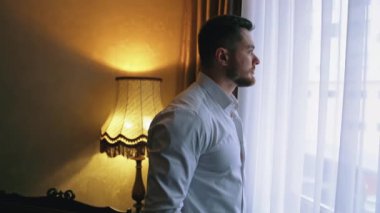 Dairedeki işten sonra yakışıklı bir adam. Karanlık otel odasındaki pencerenin yanındaki genç işadamı. Bir adam otele geldi..