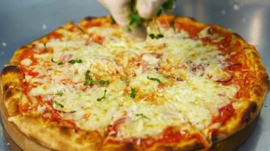 Cook hazır pizzayı süslüyor. Şefin eli eldivenli. Restoranda fırında pişmiş pizzaya taze yeşil lahanalar serpiştiriyor. Yakın plan..