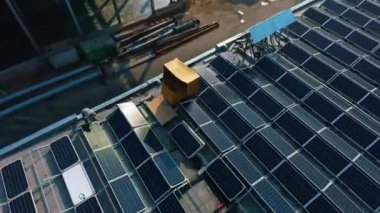 Çatıda yeni güneş panelleri var. Büyük sanayi fabrikasının tepesine mavi fotovoltaik hücreler inşa etmek. Yenilikçi koleksiyoncular çatıda. Üst hava görüntüsü.