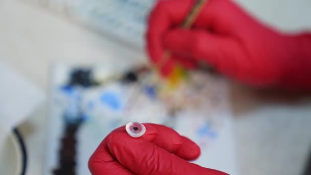 研究室で眼科を作る ブラシで人工眼を描いた医療手袋のプロのアーティスト 眼科コンセプト クローズアップ — ストック動画