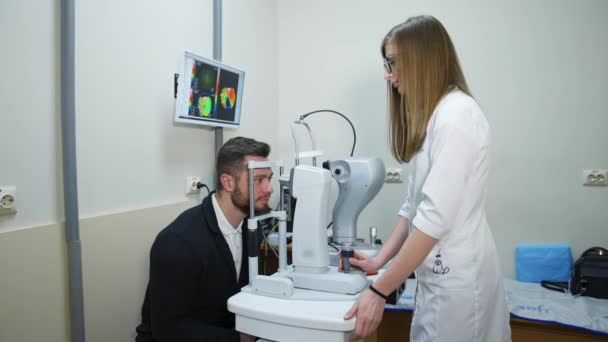 Przystojniak Sprawdza Oczy Klinice Młoda Lekarka Sprawdzająca Wzrok Pacjenta Nowoczesną — Wideo stockowe
