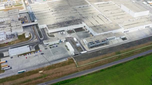 グリーンフィールド近くの巨大産業 夏の駐車場を備えた近代的な工場の工業建物のルーフ トップ アエリエルビュー — ストック動画