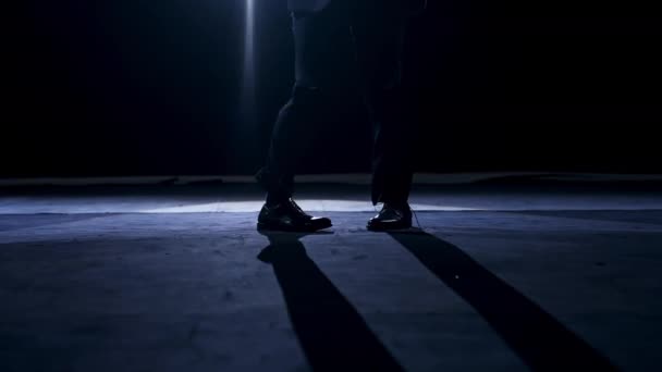 移動中のダンサーの足 暗い光の中でステージで踊るズボンと靴の男 — ストック動画