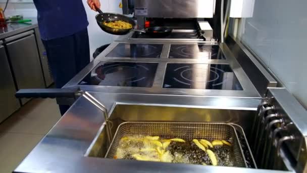 キッチンレストランのディープフライヤー シェフはフライパンで料理をしています 熱い沸騰した油で揚げるクリスピージャガイモ おいしい食事 — ストック動画