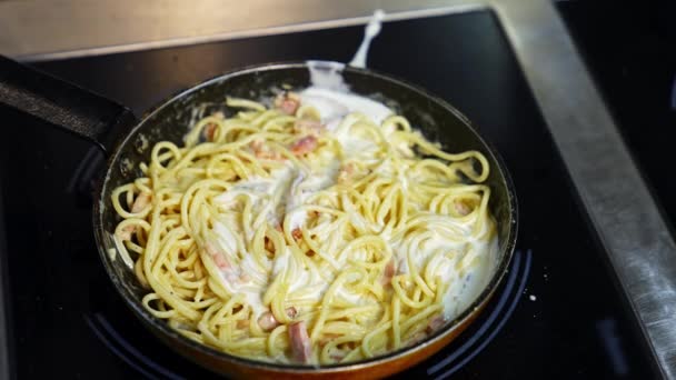 フライパンでおいしい料理の準備 フライパンでホワイトソースでスパゲッティを調理してかき混ぜます クローズアップ — ストック動画