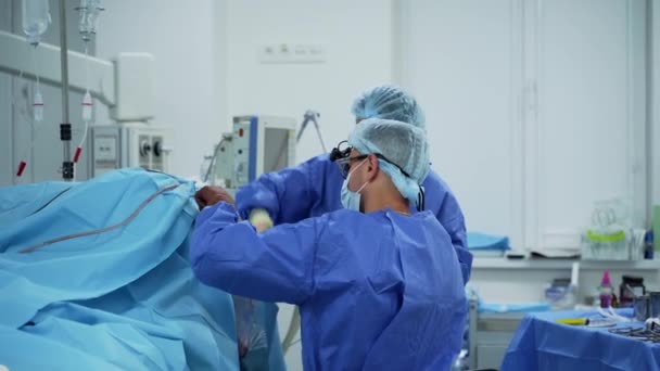 クリニックでの外科手術 医療機器や機器の背景に関する外科医の仕事 オペレーティングシアターのドクターとアシスタント — ストック動画