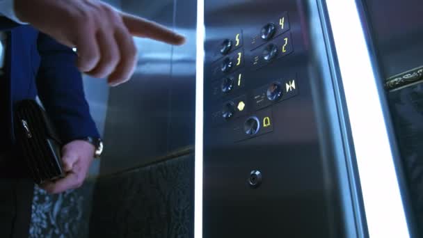 エレベーターでビジネスマン 男性の手押しボタンはエレベーターの中を動き始める ホテルや高層ビルのエレベーターボタンに触れる — ストック動画
