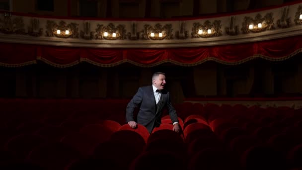 空っぽの劇場で失望した俳優 空いている赤い席に立って誰かを呼ぶ衣装の男 オペラハウスに聴衆はいない 世界のパンデミック — ストック動画