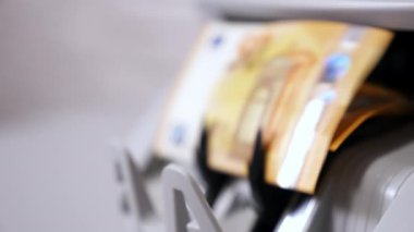 Sayma makinesine Euro para birimi. Makinede 50 Euro 'luk banknotlar sayılıyor. Sayma mekanizması avro işliyor. Kadın eli para alıyor. Yakın plan..
