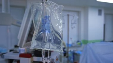 Ameliyathanede bir damlatıcının parçası. Cerrah ekibi ameliyat yapıyor. Cerrahi işlem sırasında steril ilaç paketi. Yakın plan..