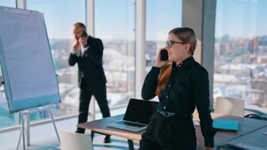 Modern ofisteki kurumsal işlerle meşgul insanlar. Patronu telefonda konuşurken gülümseyen kadın telefonda konuşuyor..