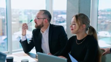 İçerideki iş ortakları. İş adamı ve güzel kadın ofis odasındaki masada birlikte oturuyorlar. İş toplantısı konsepti.