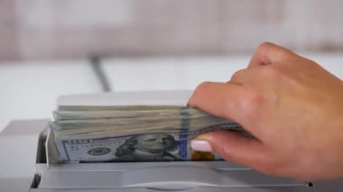Kağıt para saymak için elektronik ekipman. Banka çalışanı hesaplama için hesap makinesine 100 dolarlık banknotlar koyuyor..