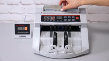 Bankadaki operasyonlar sayılıyor. Otomatik mekanizma 100 dolarlık banknotları sayıyor. Bankada elektronik sayma makinesi.