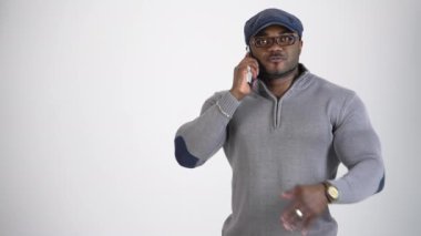 Telefonda konuşan yakışıklı bir Afrikalı 'nın portresi. Şapkalı, şık gözlüklü, spor vücutlu ve telefonu beyaz olan Afro-Amerikan bir adam..