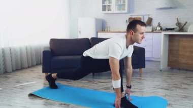 Adam evde antrenman yapıyor. Karantina sırasında paspasın üstünde egzersiz yapan genç bir adam. Evde fitness var. Sağlıklı yaşam tarzı.