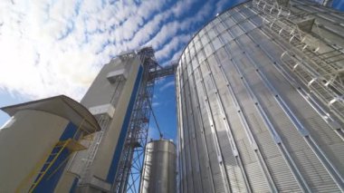 Güneş ışığında gümüş depolama tankları. Mavi gökyüzüne karşı büyük metal tahıl asansörleri. Modern tarım işleme fabrikası.