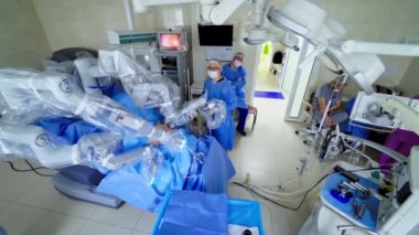 Ameliyathanede yenilikçi ekipmanlar var. Modern klinikte bir hastaya ameliyat yapan cerrahi robot. Tıbbi uzmanlar robotik sistemin çalışmalarını inceliyorlar. Üst görünüm.
