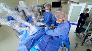 Klinikteki tıbbi robotun yanında bir grup doktor. Cerrahi odasında robotik ekipmanlı modern cerrahi. Profesyonel doktorlar mikro cerrahi yapıyorlar..