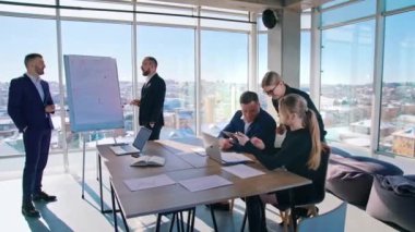 Ofisteki iş adamlarından oluşan takım çalışması. Girişimci grubu, gökdelenden şehir manzarasının arka planına ilişkin iş planları üzerinde birlikte çalışırlar..