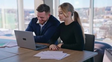 Genç işadamı ve kadın ofiste. Güzel bir girişimci kadın ve masada oturan yakışıklı bir adam iş merkezinde dizüstü bilgisayara bakıyor..