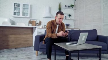 Dairesinde çalışan genç bir serbest çalışan. Evde dizüstü bilgisayarın önünde cep telefonu kullanan bir adam. Yakışıklı adam kendi işinde aletler kullanıyor..