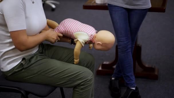 人形のダミーの実践的なコース 赤ちゃんのマネキンで患者を再生することを教える女性の実践者 インストラクターがトレーニングエクササイズを実演 — ストック動画