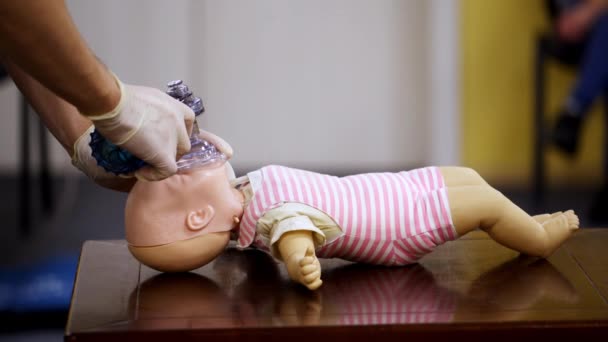 在婴儿模型上演示Cpr 在培训中心 戴着医用手套的导师在假人身上展示正确的呼吸练习 侧视图 — 图库视频影像