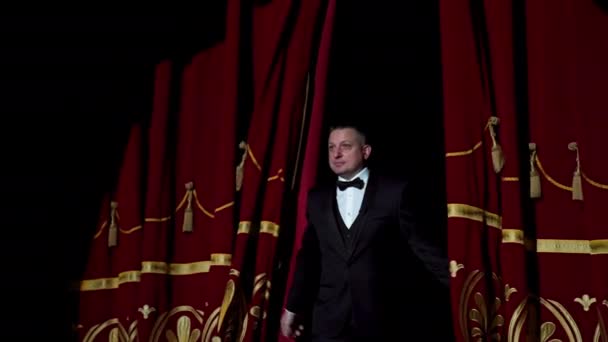 宿主的肖像 身着黑色服装的男演员出现在舞台上 并在剧场明亮的灯光下开始讲演 — 图库视频影像