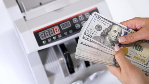 100ドル紙幣の束 自動カウントマシンの背景に多額のドル紙幣を保有する女性の手 — ストック動画