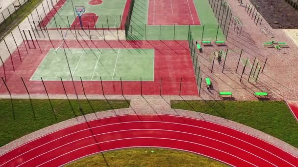 户外运动的小型体育馆 这个城市的现代运动场 红绿相间的运动场地 长着人造的青草 从上面看 — 图库视频影像