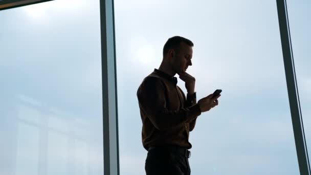 Młody Człowiek Dużym Tle Okna Biznesmen Telefonem Stojącym Biurze Patrzącym — Wideo stockowe