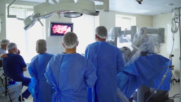 Grupo Médicos Observa Cirugía Monitor Operación Con Robot Médico Quirófano — Vídeos de Stock