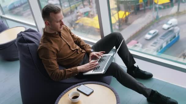 Joven Freelancer Usa Laptop Guapo Chico Está Sentado Junto Ventana — Vídeos de Stock