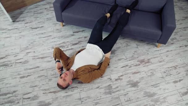 家で電話をかける若者 疲れた男は床に横たわりながら電話で働いている トップビュー — ストック動画