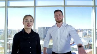 Neşeli genç girişimcilerin portresi. Güzel kadın ve erkek, iş yerindeki arka plandaki kamerada başarılarından bahsediyorlar..