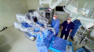 Çağdaş ameliyathanede robotik cerrahi. Minimum invaziv ameliyat sırasında robot makinenin yanında duran bir grup tıbbi uzman. Üst görünüm.
