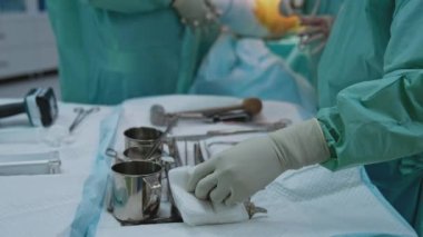 Cerrahi işlem sırasında doktor asistanı hemşire. Masadaki steril aletler ve ameliyat uzmanları ameliyathanedeki bulanık arka planda ameliyat yapıyorlar..