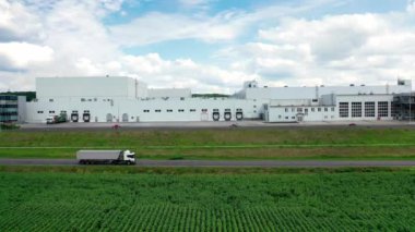 Kamyon fabrikanın arka planında bir yolda ilerliyor. Karayolu yakınında beyaz binaları olan modern sanayi fabrikası.