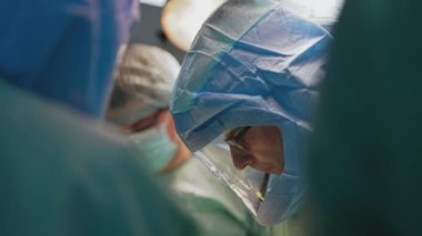 Salgın sırasında bir grup tıp uzmanı. Klinikte çalışan doktorun koruyucu şapkalı yüzünün profili. Yakın plan. Coronavirus konsepti.