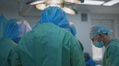 Koruyucu giysili doktorlar. Koronavirüs sırasında klinikte güvenlik üniformalı profesyonel cerrahlardan oluşan bir ekip. Covid-19. Arka görünüm.